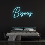 Bisous LED neon sign in blue color, placed above a stylish bed, suitable for vibrant bedroom decoration