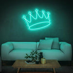 Teal crown LED neon sign illuminated in a living room with a white sofa and coffee table.