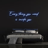 Everything you need is inside you neon sign in blue, beautifully displayed above a modern bedroom setup.