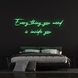 Everything you need is inside you neon sign in green, providing a vibrant glow in a modern bedroom.