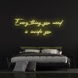 Yellow "Everything you need is inside you" neon sign bringing warm lighting and cozy aesthetics to a bedroom wall.