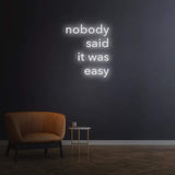 Minimalist 'Nobody Said It Was Easy' LED neon sign in white, perfect for any space, providing a motivational message that encourages you to overcome obstacles.